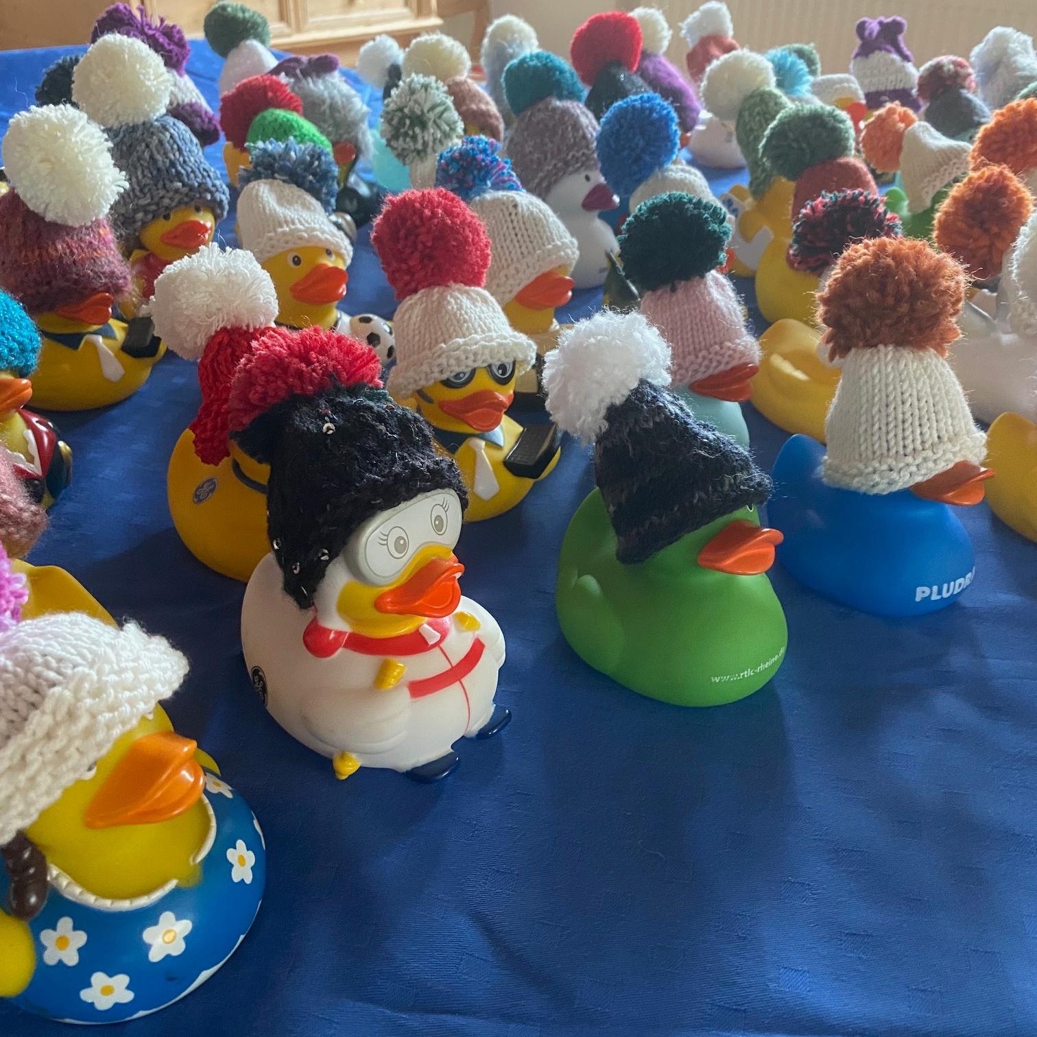 bunte Badeentchen, die kleine, gestrickte Mützen in verschiedenen Formen und Farben tragen